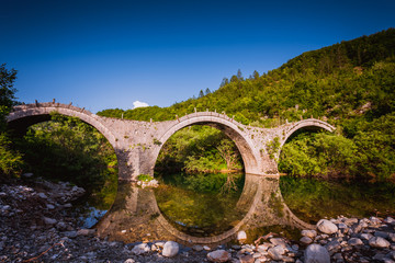 Arches stone bridge of Kalogeriko on the river of Voidomatis. Central Zagoria, Epirus, Greece.