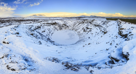 Panoramic view of the Kerid Volcano  Iceland with snow and ice in the volcanic crater lake in Winter under a blue sky © Sander Meertins
