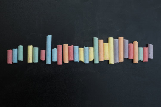 Group of multicolored chalks on black chalkboard