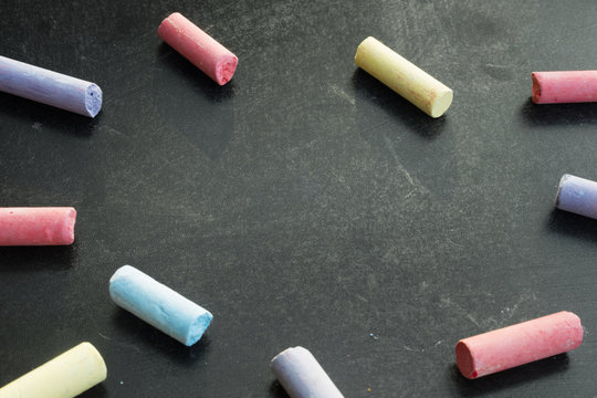 Group of multicolored chalks on black chalkboard