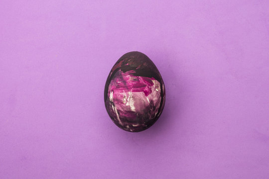 Detail of painted purple Easter egg in pink background