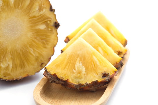 slice of pineapple on wooden plate.