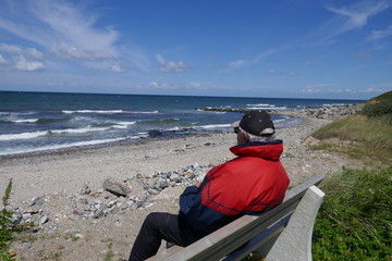 Fototapeta premium Einsamer Alter Mann sitzt auf einer Bank am Meer