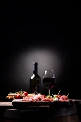 Rolgordijnen Assorted meats and  cherry mozzarella cheese, on a wooden cutting board with bottle of wine and glass on background. Italian antipasti © Fabio Balbi