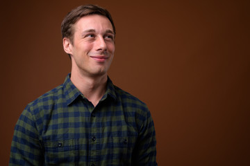 Obraz premium Young handsome man against brown background