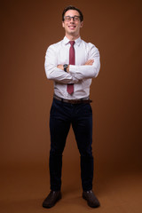 Young handsome businessman wearing eyeglasses against brown back