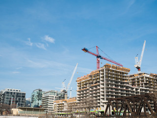 four cranes, new condos under construction in the foreground and some completed condos in the background against a large blue sky