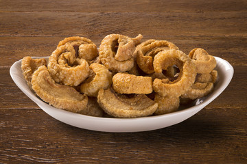 Pile of fried bacon cube portion in a white plate on wood background.