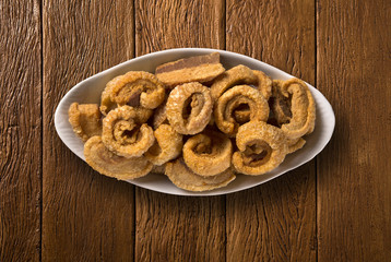 Pile of fried bacon cube portion in a white plate on wood background.