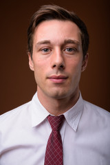 Young handsome businessman against brown background