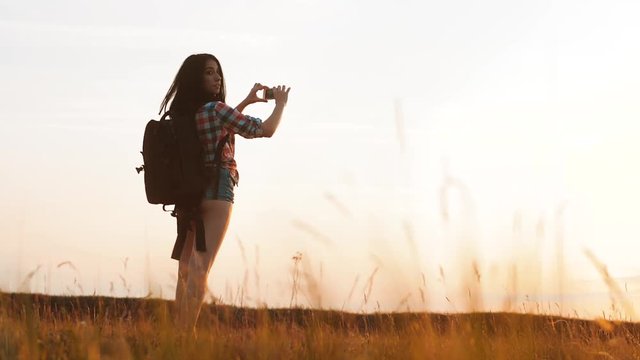 Hipster hiker silhouette girl is shooting video of beautiful nature sundown on cell telephone smartphone slow motion video. Female tourist is taking photo with mobile phone camera. female girl
