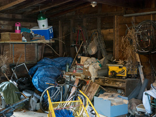 Dirty old wooden garage or shed filled with a chaotic mess of all kinds of stuff