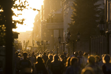 Silhouette crowd of people walking down the street at summer sunset