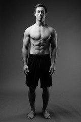 Naklejka premium Studio shot of young muscular handsome man shirtless in black an