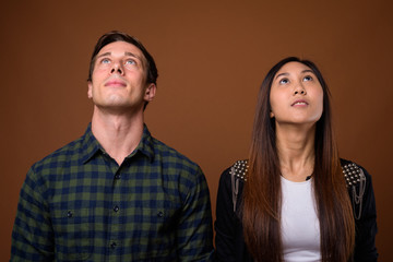 Studio shot of young multi-ethnic couple together against brown 