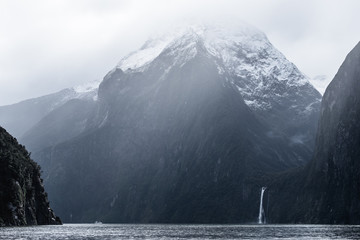 A stunning scene of nature with snow mountain and waterfalls at Milford Sound, New Zealand.