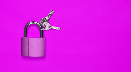 Golden closed lock with keys on a violet background. Copy space. Top View.