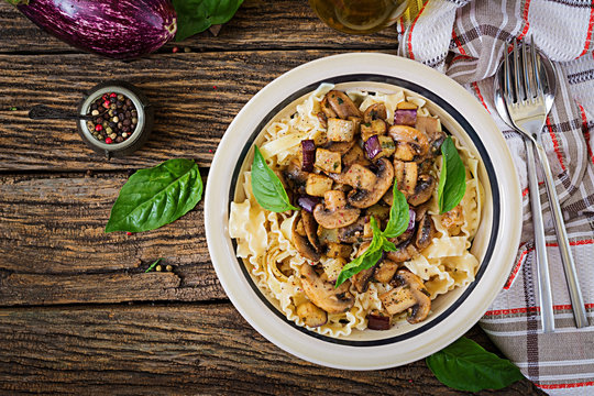 Vegetarian pasta with mushrooms and aubergines, eggplants. Italian food. Vegan meal. Top view. Flat lay.