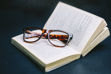 Glasses on open book with dark background