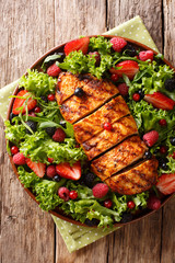 Summer healthy salad of grilled chicken breast, fresh berries, lettuce close-up on a plate. Vertical top view