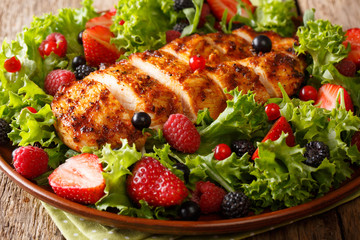Healthy paleo food: fried chicken breast with fresh berries, leaf salad close-up on a plate....