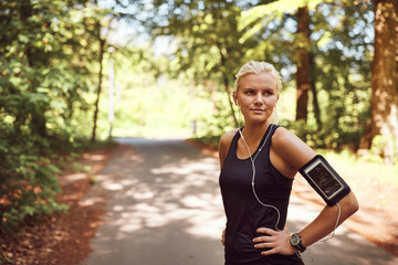 Fit young woman listeing to music before her forest run