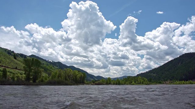Snake river flowing on beautiful day in Wyoming durning Spring runoff with big fluffy clouds.