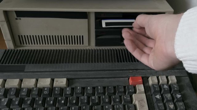 Someone inserting and removing an old-style floppy disk
