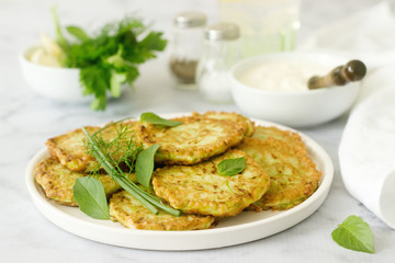 Pancakes from zucchini, served with sour cream or yogurt and various herbs. Useful vegetarian food.