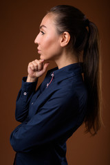 Studio shot of young beautiful businesswoman against brown backg