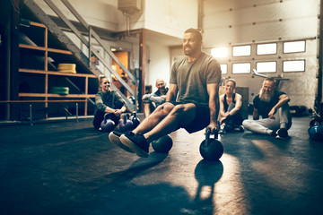 Fit young man working out in front of gym friends