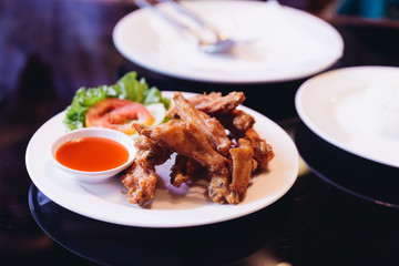 Fried chicken wings with salt served with chili sauce.