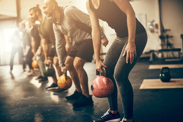 Fit people lifting dumbbells together during a workout session - obrazy, fototapety, plakaty