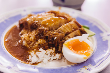 Crispy pork belly with rice pouring with gravy served with half of boiled egg.