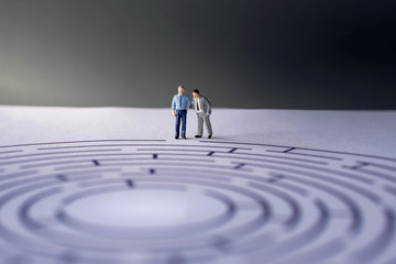 Challenge and Success Concept. present by two Miniature Figure of Businessman standing on the Maze Paper. one of them act like a Coach or Boss