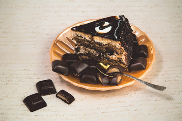 a cut piece of chocolate cake on a yellow pearl plate with pieces of chocolate tiles on a retro...