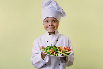funny boy chef cooked salad with vegetables, cheese and ham on a plate