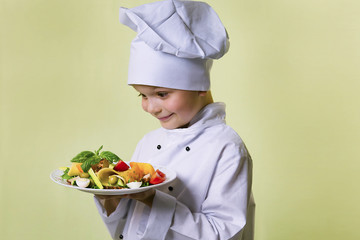 funny boy chef cooked salad with vegetables, cheese and ham on a plate