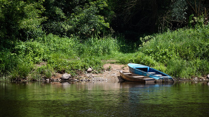 Fototapeta na wymiar Two rowing fishing boats moored on green summer beach on Neman River Grodno Belarus