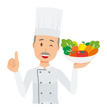 An elderly male chef wearing a cook coat has vegetables