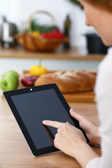 Woman cooks at the kitchen using tablet computer. Copy space area at touch pad. Healthy meal, vegetarian food and lifestyle concepts