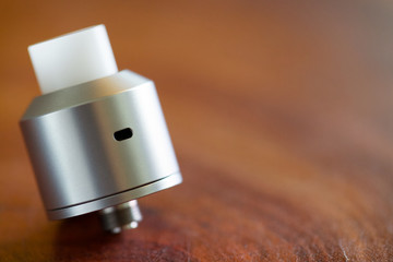 high end rebuildable dripping atomizer in simple design with white delrin drip tip on the wood...