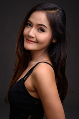 Fototapeta premium Young beautiful Asian woman against gray background