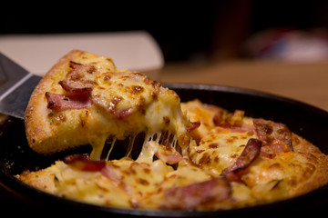 Hot pizza slice with melting cheese on a  table in restaurant pizza Italian food.
