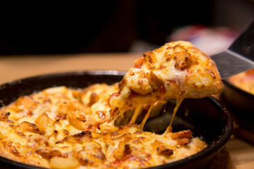 Hot pizza slice with melting cheese on a  table in restaurant pizza Italian food.