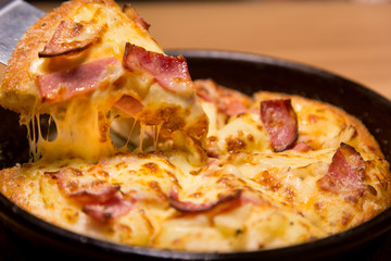 Hot pizza slice with melting cheese on a  table in restaurant pizza Italian food.