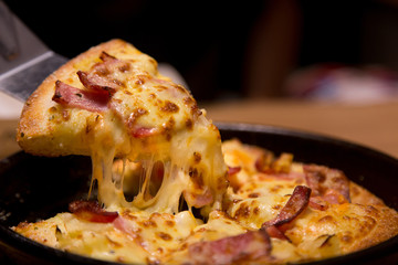 Hot pizza slice with melting cheese on a  table in restaurant pizza Italian food.