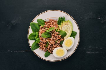 Buckwheat with avocado, spinach and boiled egg. On a wooden background. Top view. Copy space.