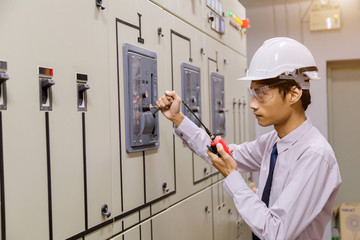 Control Room Engineer. Power Plant Control Panel. Engineer standing in front of the control panel in the control room and write the results of the measurements and check system ready .