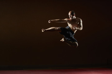 Fototapeta na wymiar Adult sportsman trains a kick in a jump